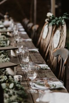 a long table with place settings and greenery on the top is set for an event