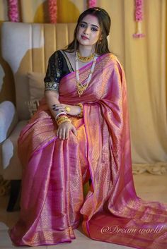 a woman in a pink sari sitting on a chair with her hand on her hip