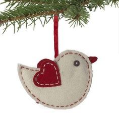 a white bird ornament hanging from a tree branch with a red heart on it