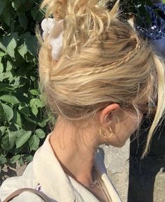 a woman with blonde hair wearing a flower in her hair and carrying a handbag