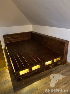 a bed made out of wooden pallets in a room with white walls and wood flooring