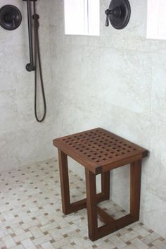 a wooden table sitting in the middle of a tiled floor next to a shower head