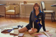 a woman sitting on the floor in front of a table with books and other items