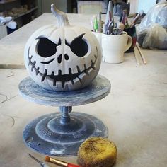 a jack o lantern pumpkin sitting on top of a cake stand next to a paintbrush