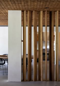 an open room with wooden columns and tables in the center, surrounded by white walls