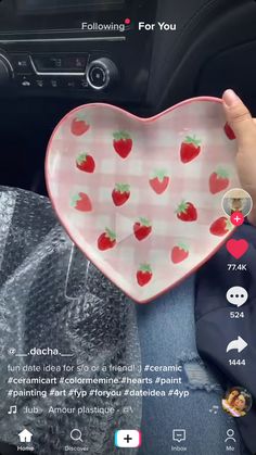 someone holding up a heart shaped plate with strawberries on it in their car seat