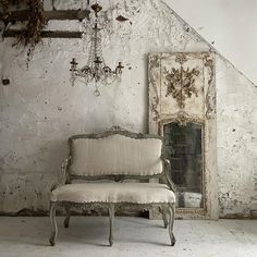 an old chair sitting in front of a white wall with peeling paint on the walls