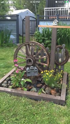 an old wagon is sitting in the middle of some rocks and grass with flowers growing out of it