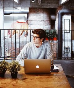 a man sitting at a table with an apple laptop