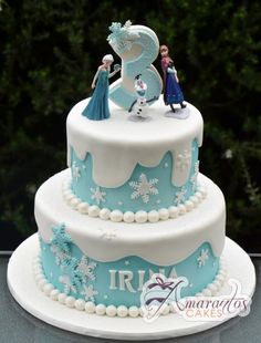 a three tiered cake decorated with frozen princess figures