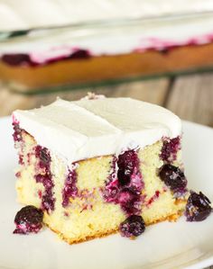 a piece of cake with white frosting and blueberries on it sitting on a plate