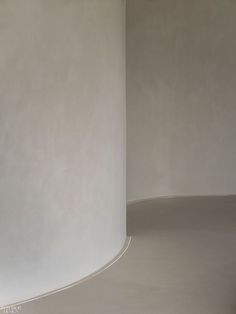 an empty room with a white round wall and yellow floor lamp in the corner next to it