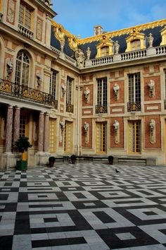 an ornate building with black and white checkered flooring on the ground in front of it