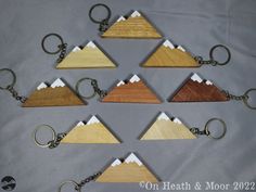 six wooden keychains with mountains on them are arranged in the shape of pyramids