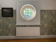 a round window in the middle of a wall with a wooden floor and wood floors