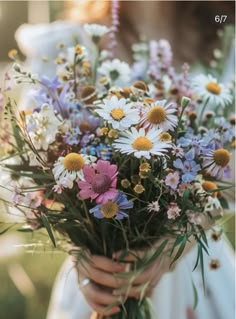 a woman holding a bouquet of wild flowers