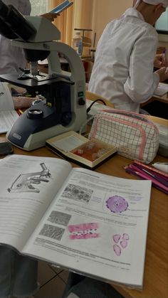 two men in white lab coats looking through microscopes at papers with drawings on them