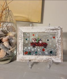 an old window frame is decorated with sea shells and other seashells in a glass vase