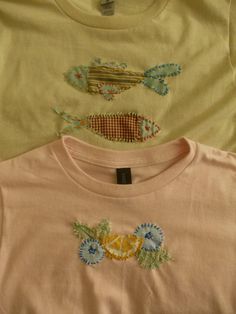 three t - shirts with embroidered fish on them sitting next to each other in a row