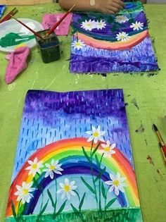 the child is painting flowers and rainbows on paper