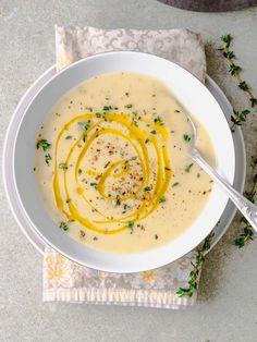 a white bowl filled with soup sitting on top of a table next to a napkin