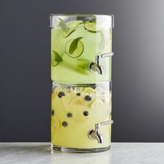 two glass containers filled with lemonade and cucumber slices