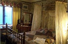 a bedroom with a bed, dresser and window covered in curtained drapes