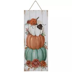 a wooden sign with pumpkins and flowers on it, hanging from a wall or door