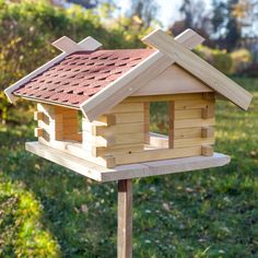 a wooden bird house on a post in the grass