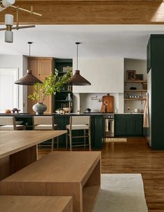 an open kitchen and dining room with wood flooring, green cabinets and wooden stairs