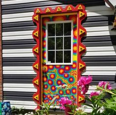 a colorful door is painted on the side of a building with flowers in front of it