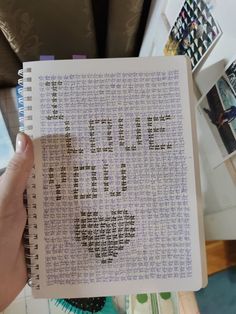 someone is holding up a cross stitch book with the word love written in cursive writing