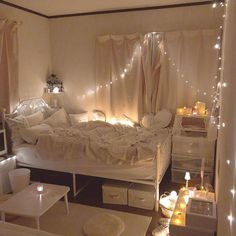 a bedroom with white furniture and fairy lights