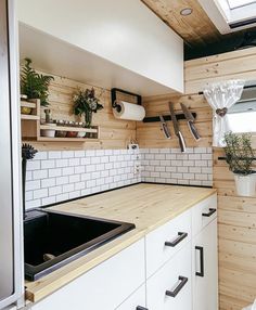 a kitchen with wooden walls and white cupboards next to a black stove top oven