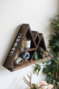 a shelf that has some plants and rocks on it, along with other items such as candles