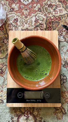 a wooden bowl filled with green liquid on top of a scale