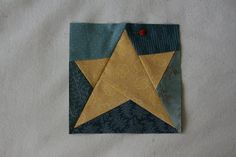 an origami star is placed on a piece of paper with blue and gold fabric