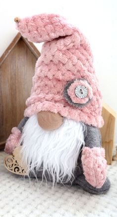 a small stuffed animal is wearing a pink hat and gray pants with white fur on it