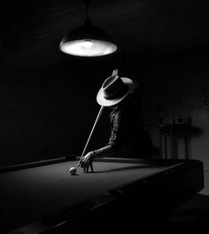 a man in a hat is playing pool