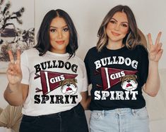 two women wearing wildcat girls spirit t - shirts standing next to each other in front of a wall