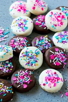 chocolate covered donuts with white frosting and sprinkles on a table