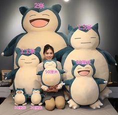 a woman sitting in front of large stuffed animals with their names written on the faces