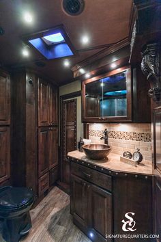 a bathroom with wooden cabinets and a skylight above the sink, along with a black toilet