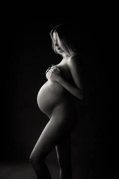 a pregnant woman in black and white poses with her hands on her hips while wearing tight stockings