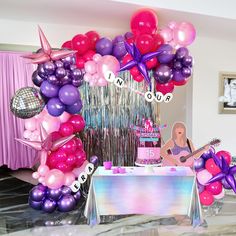 a birthday party with balloons, streamers, and guitar on the table in front of it