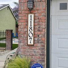 a house number sign on the side of a brick wall next to a garage door