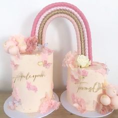 two cakes decorated with pink flowers and gold trim, one has a rainbow on top