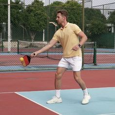 a man holding a tennis racquet on top of a hard surface tennis court