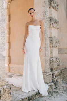 a woman in a white wedding dress posing for the camera with her hand on her hip