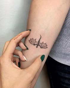 a woman's arm with a leaf tattoo on it